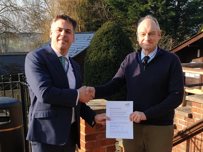 Head of boarding Fred Pennell and headteacher Jonathan Hetherington holding the Ofsted report in front of the school entrance