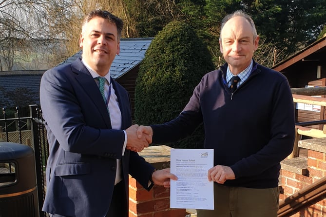 Head of boarding Fred Pennell and headteacher Jonathan Hetherington holding the Ofsted report in front of the school entrance