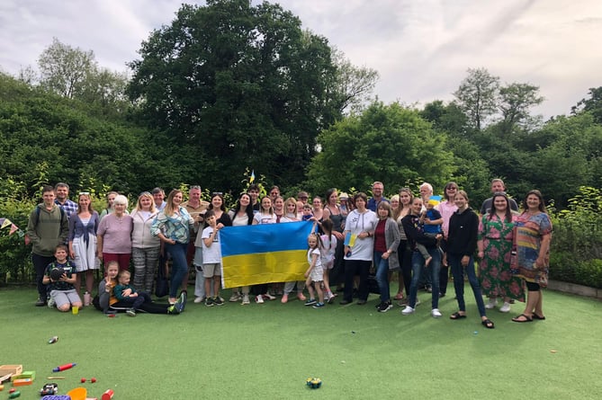 The Ukrainian guests and their host families fly the flag of Ukraine at Lindford Village Hall