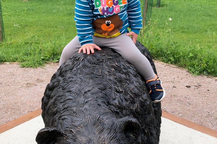 Montgomery, the bronze Erie Wood Bear at Headley Down Nature Reserve, gives a child a ride.
