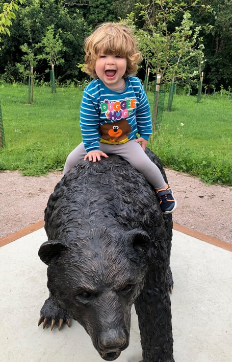 Montgomery, the bronze Erie Wood Bear at Headley Down Nature Reserve, gives a child a ride.