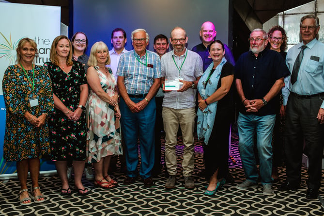Senior ranger Jamie Cummins accepts the Land Trust’s national Community Space of the Year Award for its management of Hogmoor Inclosure in Bordon on behalf of the Deadwater Valley Trust at Old Thorns in Liphook on July 12th 2022. From left: Sian Manning, Emma Fyfield, Sarah Burch, Nora Dobson, Bruce Collinson, Bob Betteley, Paul Charman, Jamie Cummins, Alan Carter, Julie Reid, Brendan Finnegan, Marie-Anne Phillips and Bill Wain.