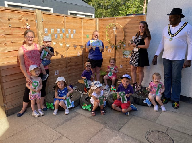 Whitehill town mayor Cllr Leeroy Scott, right, presents Town in Bloom rosettes and certificates to children at Tiny Tops nursery, Wolfe Lodge, Farnham Road, Bordon, August 10th 2022.