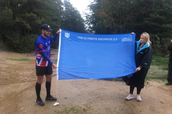 Brian Wood unfurls his Ultimate Sacrifice Challenge flag at the finish of his 35th marathon in 35 days, Hogmoor Inclosure, Bordon, November 7th 2022.