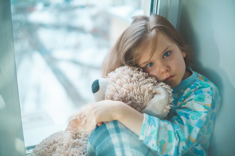A sick child with a fever sitting at home in quarantine