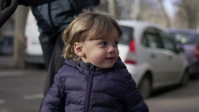 Cute little toddler walking in street sidewalk outside with mom
