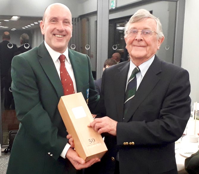 Alresford captain Simon Freemantle (left) presents David Harrison with a 50-year-old bottle of vintage port to mark the 50th year of Hampshire playing against Alresford since 1971 after David founded the fixture after he became county captain. COPYRIGHT HAMPSHIRE GOLF. NOT FOR SYNDICATION. FREE to use in reports in print and online of Hampshire Golf matches and championships ONLY.