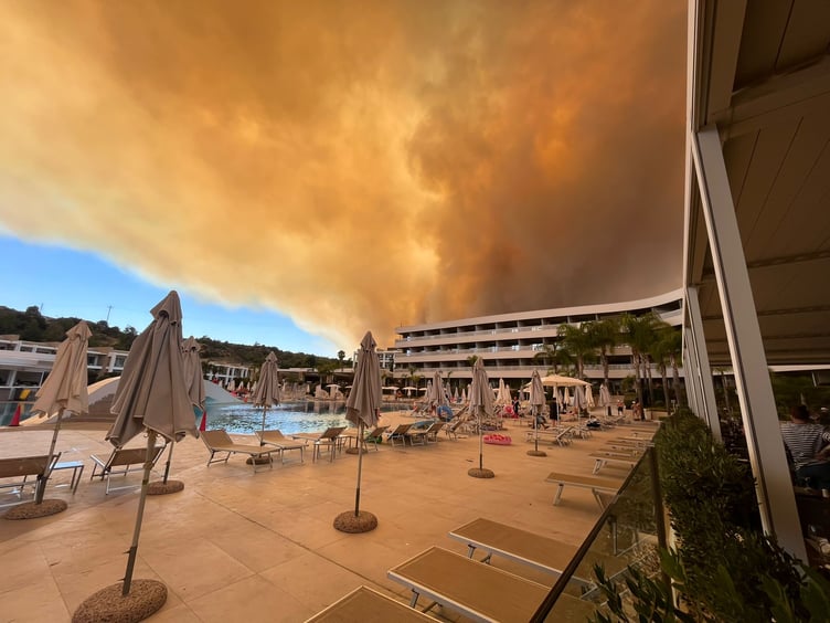 Smoke from the wildfires on Rhodes loom over the hotel. Guests had to literally run for their lives after being ordered out by the Greek army.