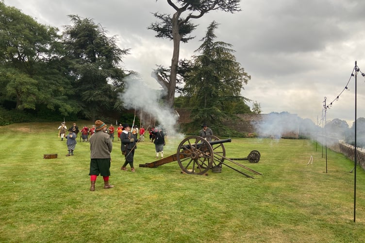 Am English Civil War-era gun crew fire a shot from the Great Lawn at Farnham Castle during Heritage Open Days 2023