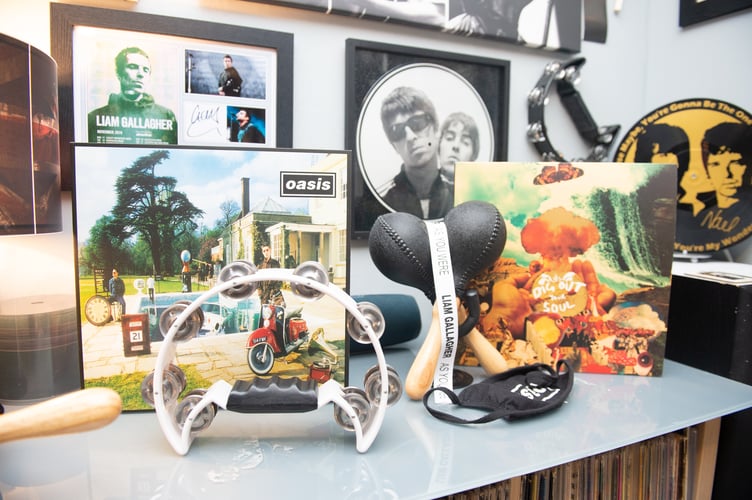 Oasis superfan John Smallbones Oasis memoribillia inside his home in Hampshire. See SWNS story SWOCoasis; Meet the Oasis superfan who has spent THOUSANDS on band memoribillia including life size cut outs of the Gallagher brothers - and his fiancee isn't even a fan. John Smallbones, 45, fell in love with the band back in 1992 and was devastated when the brothers went their separate ways. Over the past decade, window surveyor John has spent thousands of pounds on Oasis merchandise including vinyls, clothing and life size cutouts of both Gallagher brothers. He's even got Oasis tattoos and has named his business 'Wall of Glass' after the popular 2017 Liam Gallagher hit with a van plastered in stickers dedicated to the boys. His home is covered top to bottom with Oasis memorabilia, much to the amusement of his extremely patient fiancee Elaine, 46, who isn't even a fan of the band.