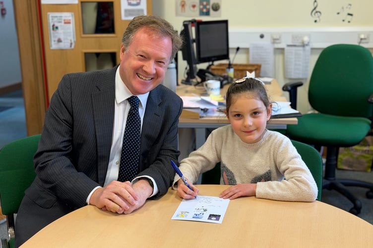 Farnham and Bordon MP Greg Stafford with the winner of his Christmas card competition, Isabelle, a pupil at St Peter's C of E Primary School in Wrecclesham.