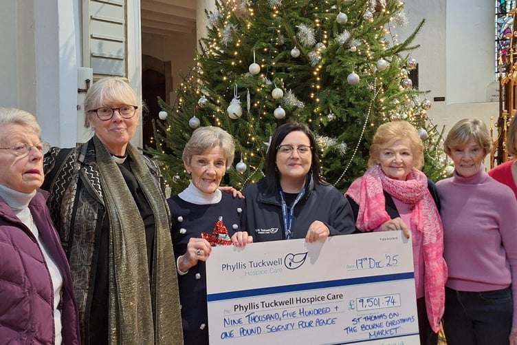 Sam West, community fundraiser at Phyllis Tuckwell, is presented with a cheque from organisers of St Thomas on the Bourne Church’s Christmas market.