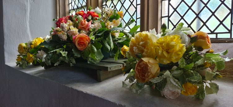 A window ledge with three floral arrangements for Choral Evensong in St Petrock's Church, Timberscombe.