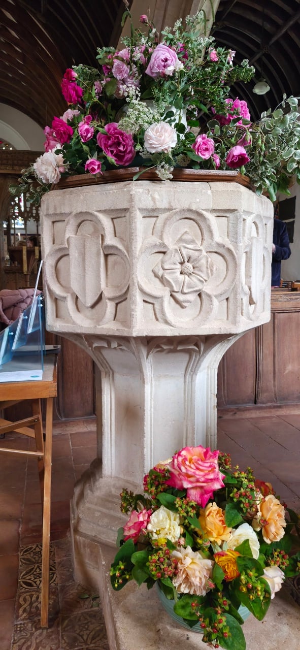 The font of St Petrock's Church, Timberscombe, surrounded with roses for Choral Evensong.