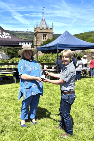 The Rev Nicola Butt receives the raffle first prize from churchwarden Kate Hart during Timberscombe's patronal festival family fun day.