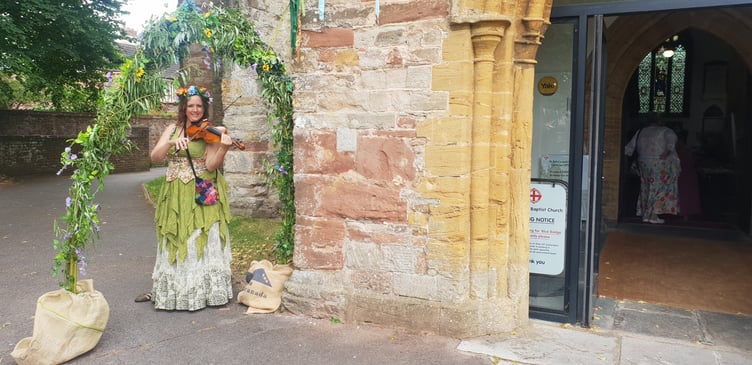 Violinist Laura Gilham is framed by a willow arch through which a human circle was formed for 'clipping the tower' at St John's Church, Wellington.