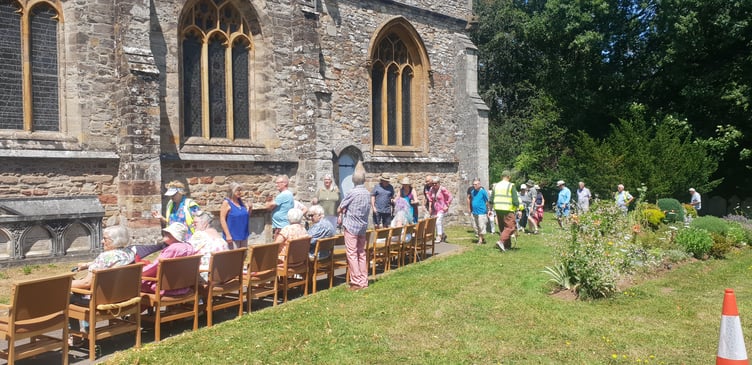 The lead group of visitors reappears at the head of a column encircling St John's Church.
