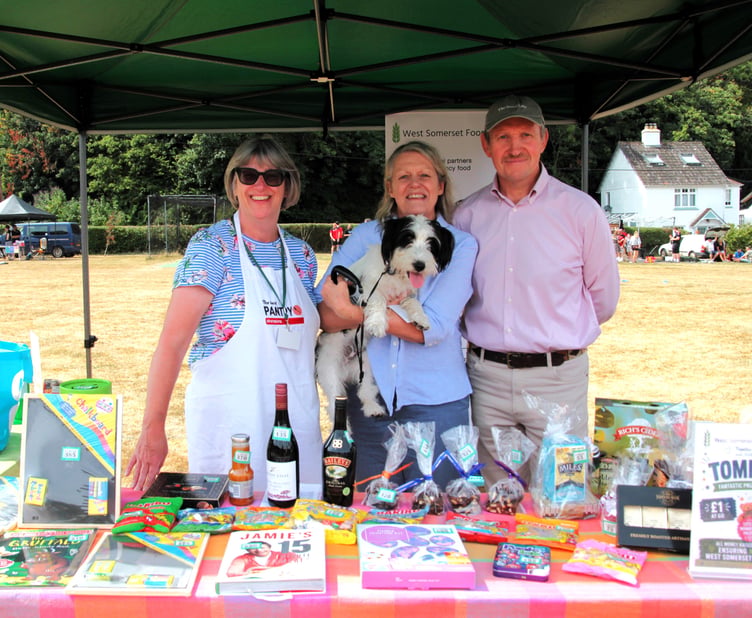 West Somerset Food Cupboard volunteers Alex Groves, Trudi and Phillip Mann, with Arlo the dog, attending Porlock Country Fair. PHOTO: George Ody.
