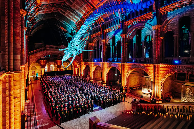 Rock Choir members perform for Sir David Attenborough under the Natural History Museum's famous whale skeleton.